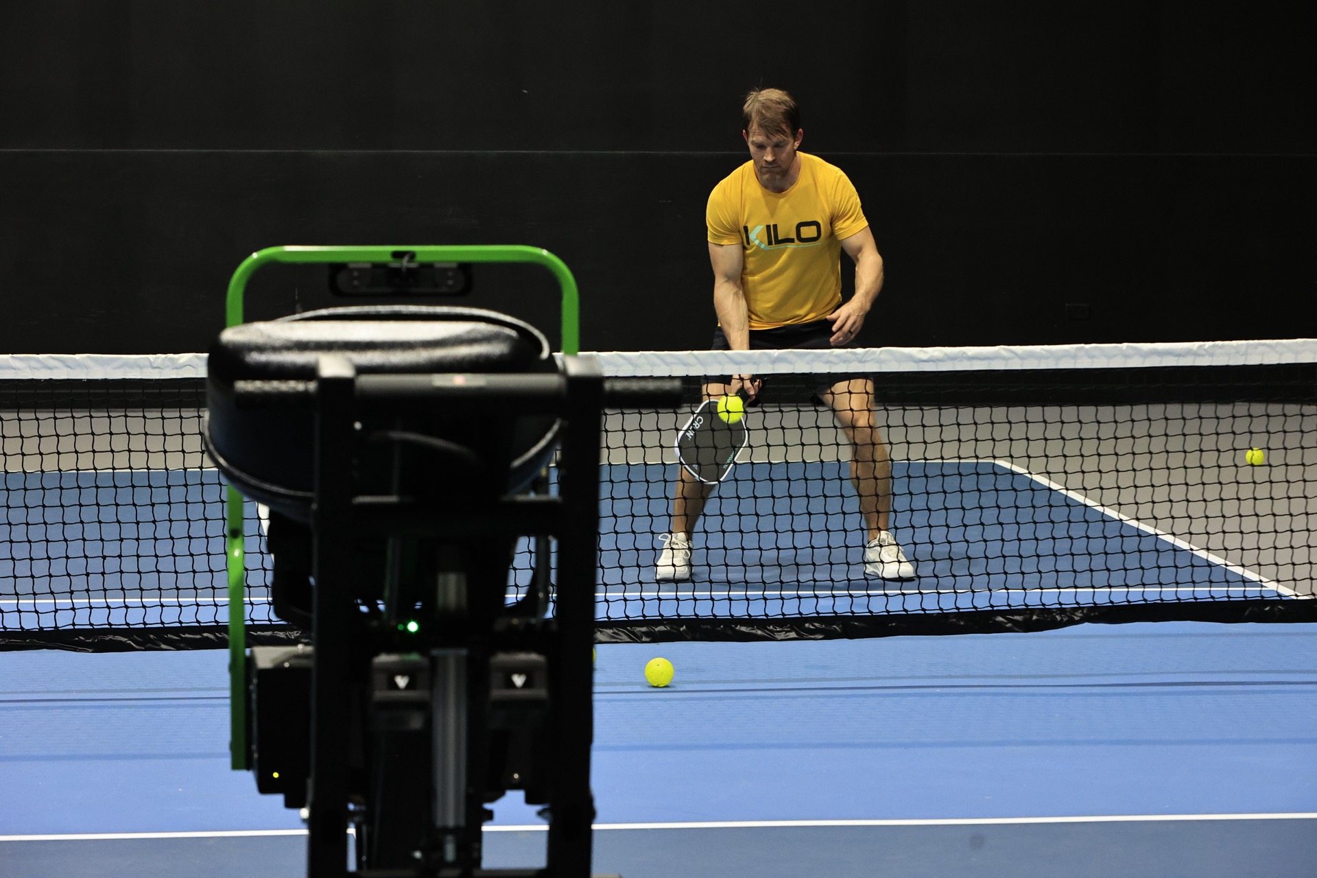 A member rallying with the Volley trainer on an indoor pickleball court